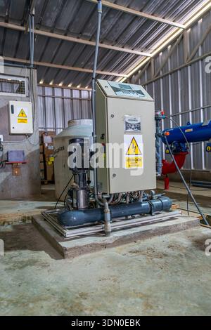 Industrial electrical control panel with booster pump and piping inside water treatment facility and utility plant. Stock Photo