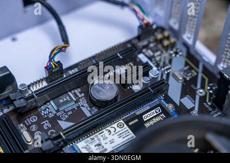 Macro close up of computer motherboard with SSD, PCIe slot, wiring and cooling hardware inside modern desktop system. Stock Photo