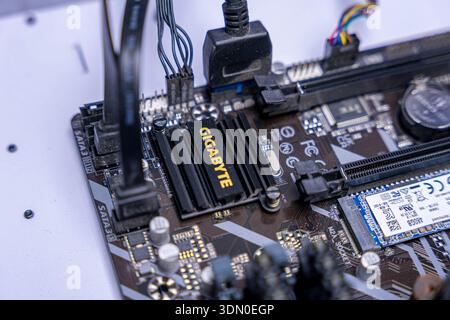Macro close up of computer motherboard with SSD, PCIe slot, wiring and cooling hardware inside modern desktop system. Stock Photo
