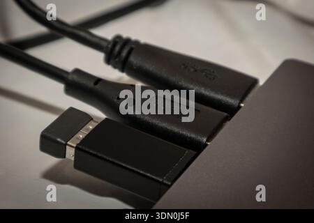 Close-up of black USB and HDMI cables connected to a laptop, showing texture detail and technology interface under neutral lighting. Stock Photo