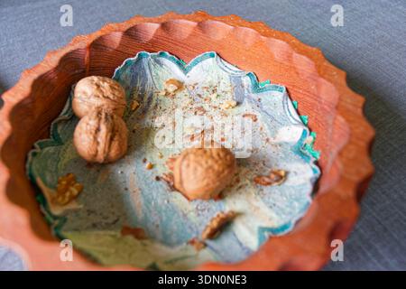A carved wooden plate holds an embroidered napkin and three walnuts, arranged neatly on a table to create a simple rustic still life with natural text Stock Photo