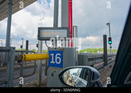 A Oeresund toll lane marker shows number six and the word Godtur, seen beside the left side window and mirror. A gray car reflects in the glass as dri Stock Photo