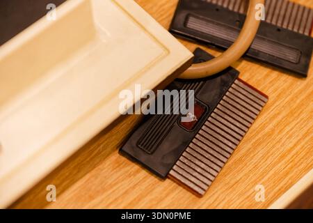 Two small electronic modules sit beside a hose on a work surface, one has comb like fins and a number three mark, creating a close technical view of u Stock Photo