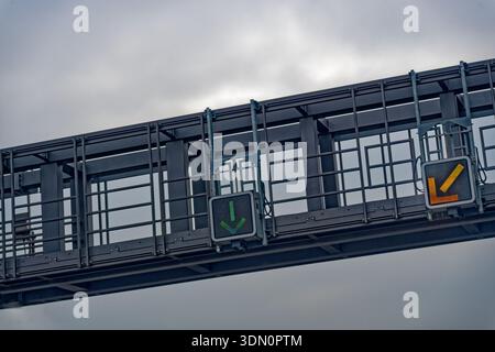 Modern overhead traffic control system with green arrow signal on a steel bridge structure under cloudy sky. Concept for traffic flow, road safety, sm Stock Photo