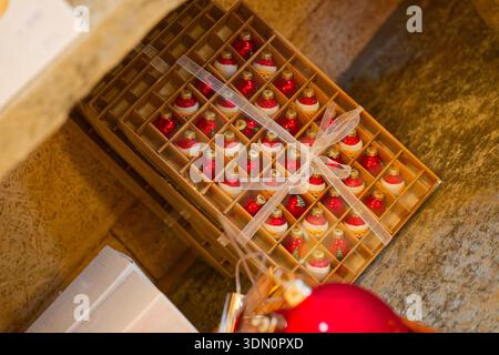 Small Christmas baubles sit in neat gift boxes, packaged like presents. The colorful ornaments look ready for decorating a tree, combining holiday dec Stock Photo