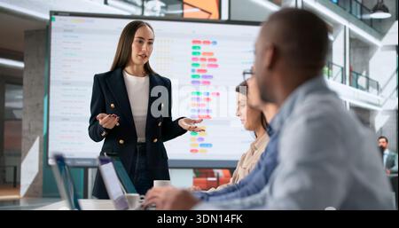 Team Of Diverse Professionals Analyzing Spreadsheets In Office With Coach. Stock Photo
