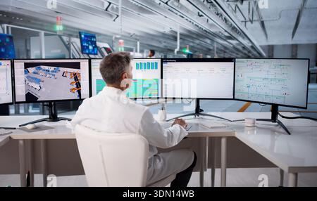 Skilled Engineer Monitoring SCADA System During Manufacturing Process In Facility. Stock Photo