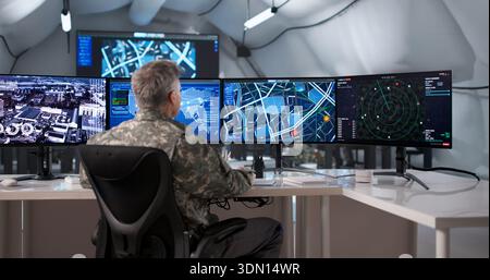Military Officer Monitoring Surveillance Data On Desktop Computer In Command Center. Stock Photo