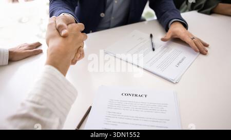 Closeup two men signing contracts and shaking hands over desk Stock Photo