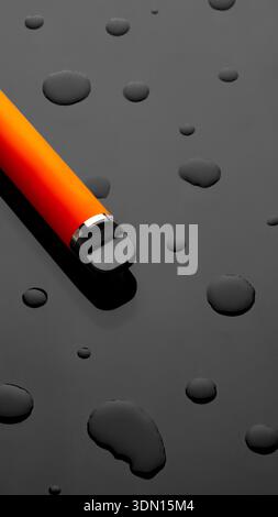 Close-up of an orange pen on a black surface with water droplets at midday Stock Photo