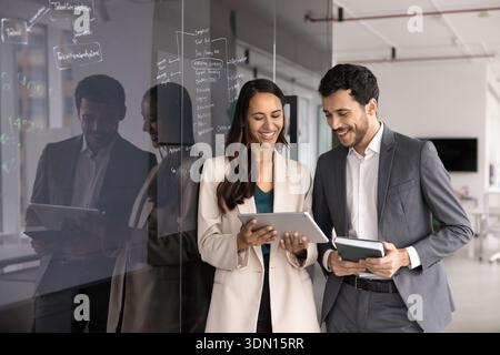 Teammates using tablet stands next to board with written notes Stock Photo