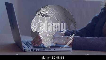 Typing female hands moving across laptop keyboard at desk, wearing dark sweater, with globe overlay Stock Photo