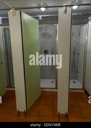 Hostel shower cabins with open doors, simple tiled interior and shared bathroom facilities in budget accommodation. Backpacking, pilgrimage Stock Photo