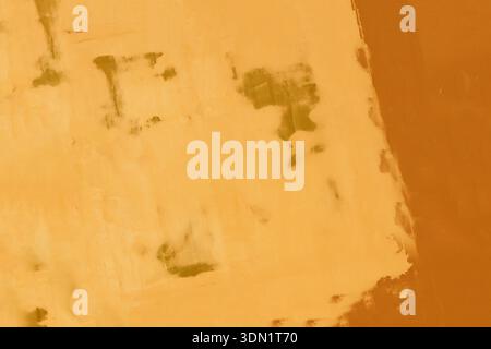 Old abandoned, damaged wall as a background. Orange, abandoned, weathered, patterned yellow-orange plaster. Stock Photo