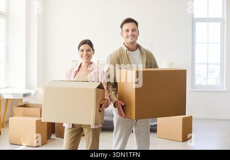Happy proud couple holding cardboard boxes to move into new home apartment Stock Photo