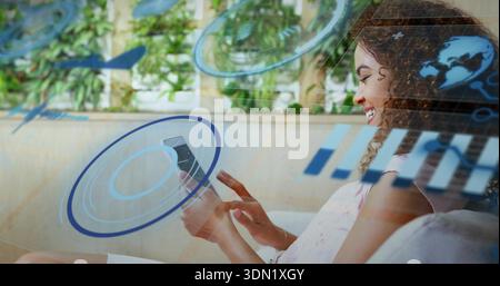 Smiling woman in sleeveless top using smartphone viewing AR-HUD on sofa, plants at home, copy space Stock Photo