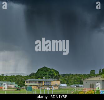 Rain fall from stormy grey sky and clouds above building in tropics Cape York, Queensland, Australia. Stock Photo