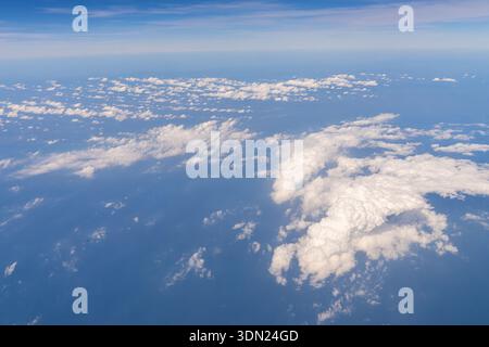 Clouds are scattered over the ocean during daytime. The blue sky stretches above, and the scene shows various shapes and sizes of clouds against the Stock Photo