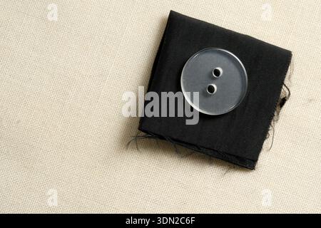 A close-up of a transparent button resting on a piece of black fabric, showcasing texture. Stock Photo