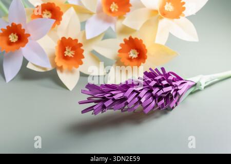handcrafted paper daffodils and purple hyacinth on a sage green background, elegant spring papercraft floral composition for creative diy and seasonal Stock Photo