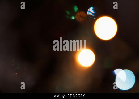Abstract bokeh bright lights in various colors, creating a festive atmosphere. Soft focus with circular shapes in green, orange, and blue hues Stock Photo