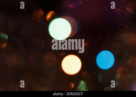 Abstract bokeh lights in various colors, creating a festive atmosphere. Soft focus with circular shapes in green, orange, and blue hues Stock Photo