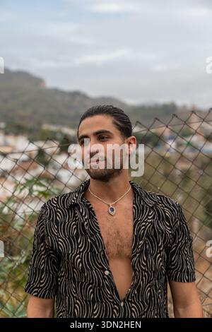 Young man contemplating outdoors, wearing stylish shirt Stock Photo