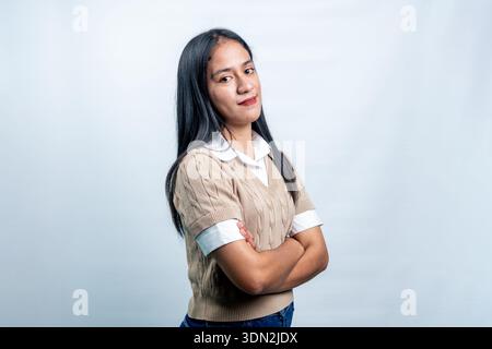 Close-up portrait of a pretty Southeast Asian woman in smart casual outfit posing confidently against a bright neutral background. Stock Photo
