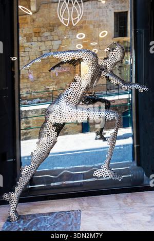 A sculpture of a man with metal circles in a shop window in Valletta on August 18, 2025 Stock Photo