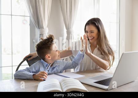 Mother giving high five to son during studying at home Stock Photo