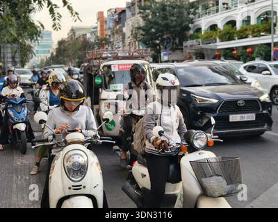 Scooter drivers using smartphones in traffic jam, typical urban congestion in Phnom Penh, Cambodia where motorbikes are a primary mode of transport. Stock Photo