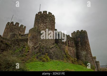 Moody grey skies provide a sombre background to the soaring medieval towers of a powerful medieval castle, Conway, North Wales. Stock Photo