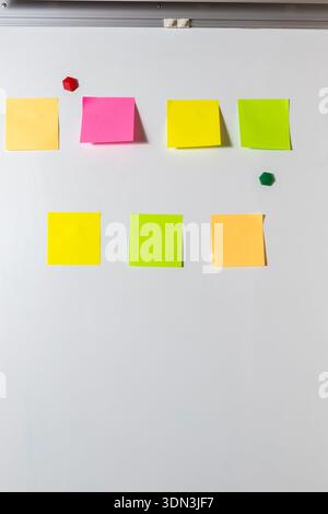 Seven colorful, blank sticky notes arranged on a white whiteboard surface. for brainstorming, team planning, reminders, concepts, and communication te Stock Photo