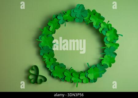 A green shamrock wreath with an additional clover decoration is arranged on a soft green background in a top view layout with copy space. Stock Photo