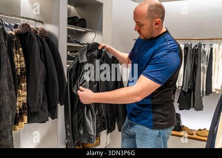 Hands examining jacket zipper and seam in closeup, focusing on stitching, hardware and leather finish for durability assessment Stock Photo