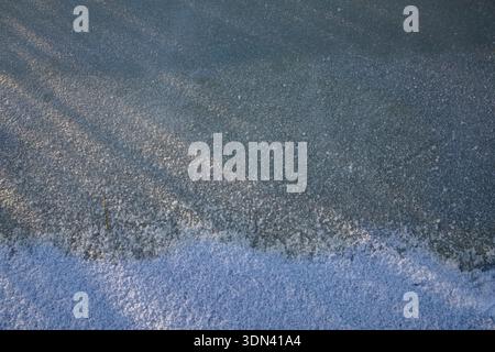 Frozen ice surface with snow layer and subtle winter light texture Stock Photo