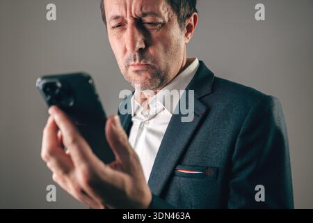 Worried businessman in suit staring at smartphone bad news, selective focus Stock Photo