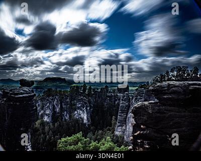 Long‑exposure landscape with dramatic sandstone pillars and fast‑moving clouds in deep blue sky. Stock Photo