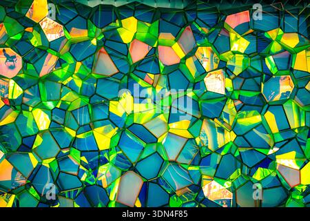 Abstract geometric glass mosaic with vibrant green blue and yellow colors creating modern stained glass texture background Stock Photo