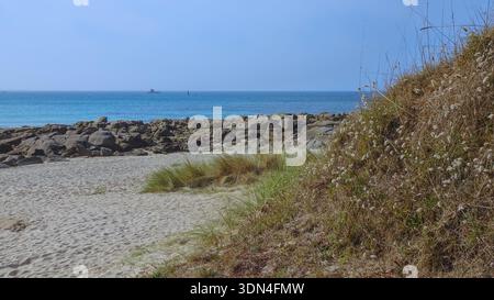 A quiet, peaceful beach with gentle rocks and rolling dunes, where the sea and sky blend in soft, serene blue tones. Stock Photo