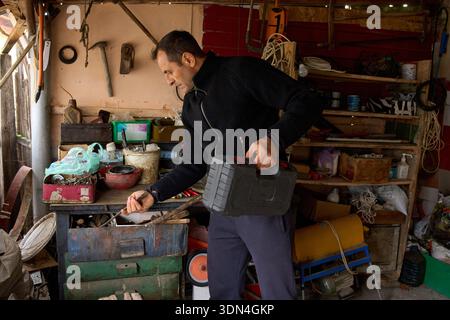 Middle-aged man searching for tools in cluttered and disorganized workshop shed Stock Photo