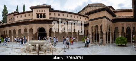 Panoramic view of the Court of the Lions at the Alhambra in Granada, showing the iconic marble lion fountain surrounded by ornate Moorish arches. Stock Photo
