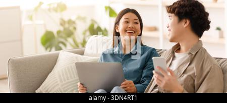 Couple Enjoying Time Together at Home While Using Laptop and Smartphone Stock Photo