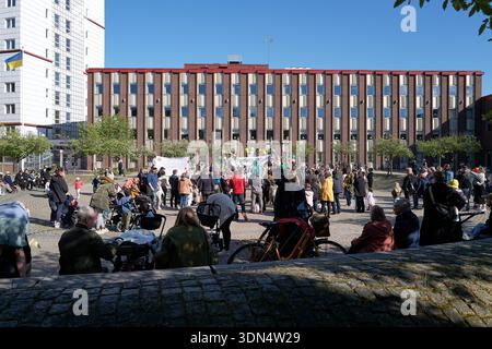 A large crowd of people are gathered in front of a building. Scene is lively and social, as people are standing and sitting together, possibly enjoyin Stock Photo