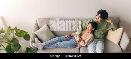 Couple Sitting on a Couch in a Cozy Living Room Enjoying Time Together Stock Photo