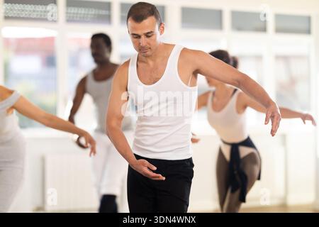 Concentrated women and men rehearsing ballet dance in class Stock Photo