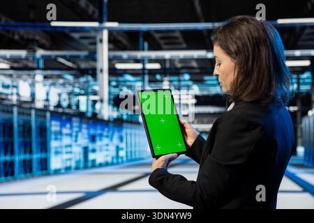 Green screen mockup tablet used by data center admin to do checkup on cloud computing infrastructure, AR overlay. Server hub computer scientist using chroma key isolated screen device Stock Photo