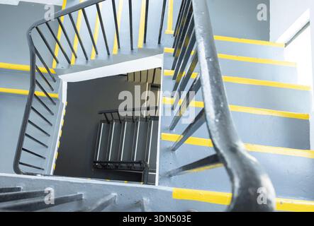 Aerial View Of Spiral Staircase With Grey Steps And Yellow Safety Edges Inside Industrial Building Stock Photo