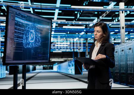 Data center computer scientist using AI to troubleshoot backend operations gear. Server hub worker running deep learning software development program on large display, resolving system crashes Stock Photo