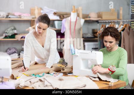 Two clothing makers working on pattern and stitching Stock Photo